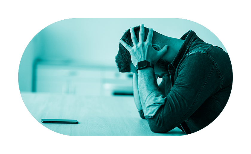 Man sitting at desk with head in hands with teal overlay