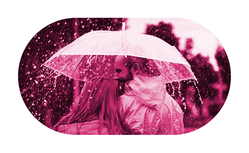 Man and woman under umbrella looking content in the rain